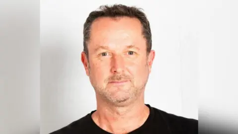 Charisma AI Guy Gadney head shot. He has short brown hair and grey stubble.