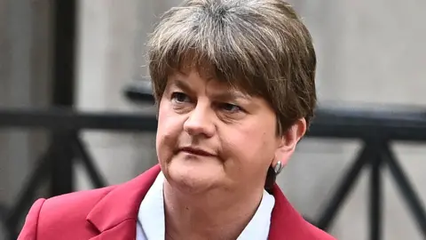 Arlene Foster pictured on her way into the NI Covid Inquiry in May 2024. She is wearing a red suit jacket and white blouse