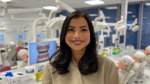 Mark Ansell / BBC Dr Amrit Chauhan in a University of Leeds School of Dentistry study space. She is smiling at the camera.