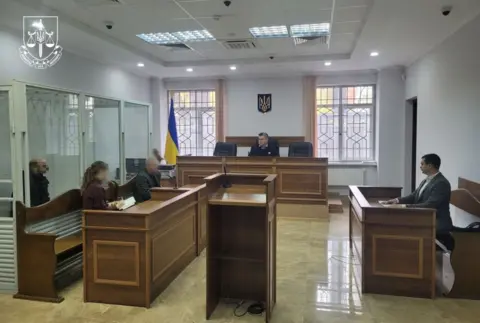 Ukrainian prosecutors office A courtroom with a man inside a glass enclosed dock