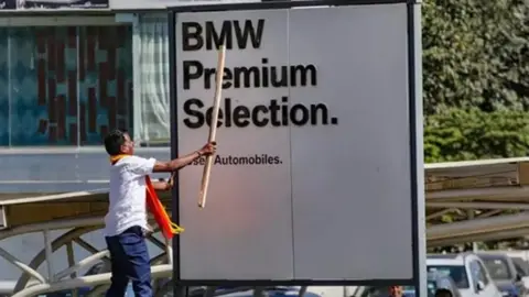 PTI A man can be seen hitting a billboard with a stick in the southern Indian state of Karnataka.