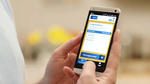 NS&I of Premium Bonds Prize Checker displayed on a phone held by two hands.