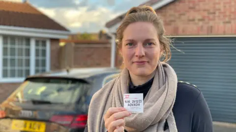 Sietske Sikkema holds her parking ticket standing next to her car