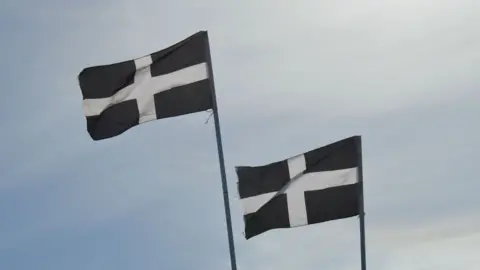 BBC Two flags of St Piran flying on flagpoles. The flags are white St George's-style crosses on a black background 