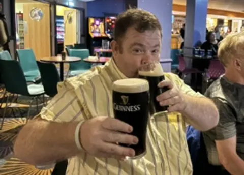 Leicestershire Police A man in a yellow shirt holds up two pints of Guinness.