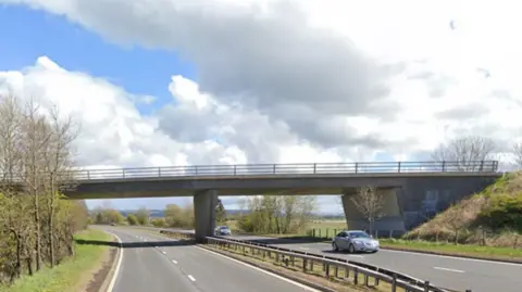 A stretch of motorway, including a bridge, with various cars travelling along it