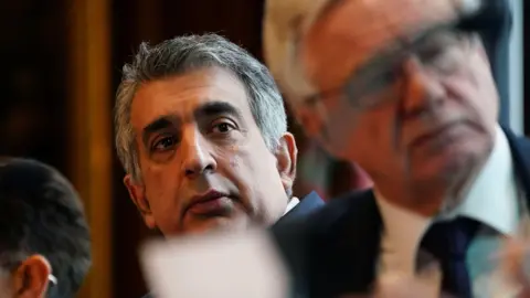 PA Media Mark McDonald, who has black hair streaked with grey, and Sir David Davis MP, who has grey/white hair and glasses, listen to one of the speakers at the press conference. 