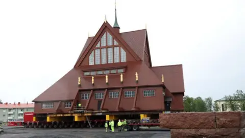 Reuters Kiruna's historic wooden church sits on a wheeled transportation unit before being moved to a new site in Kiruna, Sweden 