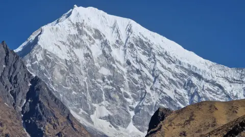 Judith Swift The mountain is completely covered in snow at the top and then gray-white downhill