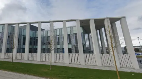 The grey exterior of Inverness Justice Centre. The outside of the building features a number of pillars.