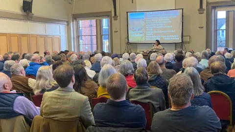 Supplied Group of people sitting facing their MP at a public meeting