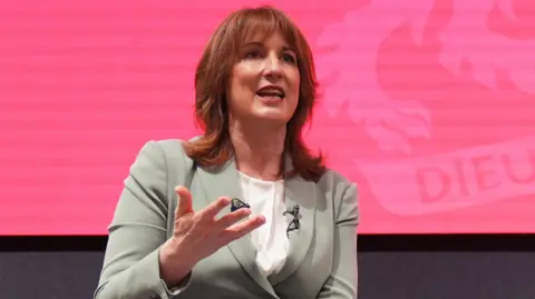 Rachel Reeves speaking against a bright pink background