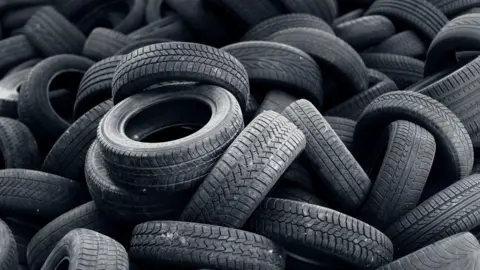 Getty Images A close-up of a large pile of used tyres, arranged haphazardly, some with their word tread facing the camera, others with their sidewalls visible