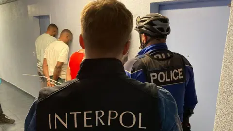 Interpol-agenten op de foto terwijl ze mensen arresteren