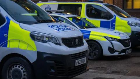 Three Police Scotland vehicles parked in a row. In the forefront is a Police Scotland van, then a Police Scotland car, then another large Police Scotland van. 