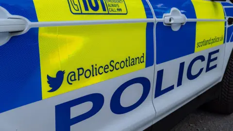 The driver side door of a police car with the words Police and Police Scotland visible 