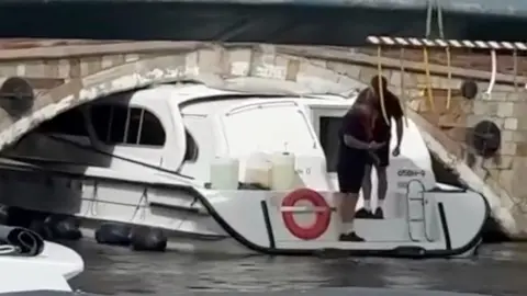 Boat stuck under a bridge on a river