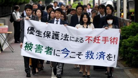 Lawyers and supporters of forced sterilisation victims  carry a banner saying "Sterilisation under the eugenics law. Relief measures for the victims required now!"