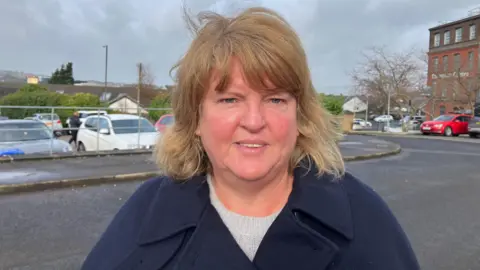 DUP councillor Niree McMorris is standing looking into the camera, she is wearing a blue coat, and a grey jumper and has short hair