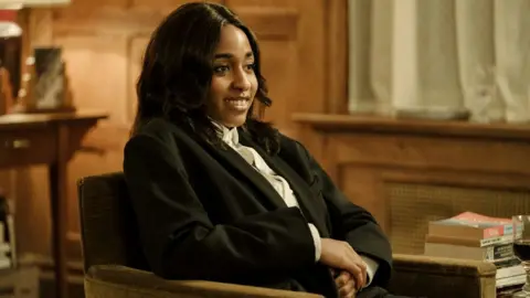 Sony Pictures Ayo Edebiri in After The Hunt, sitting in a chair wearing a suit