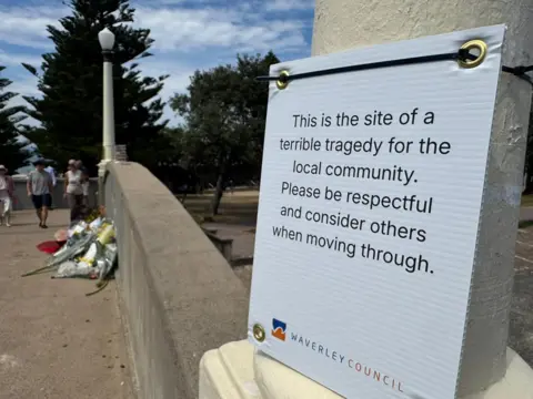 'This is the site of a terrible tragedy fro the local community. Please be respectful and consider others when moving through,' reads a sign placed at the bridge where two gunmen opened fire on a crowd of people at a Jewish festival at Bondi beach.