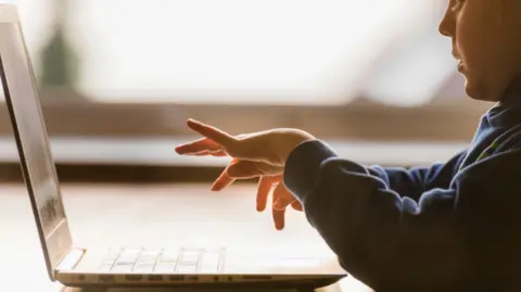 Getty Images Stock image of a young caucasian boy typing at a laptop.