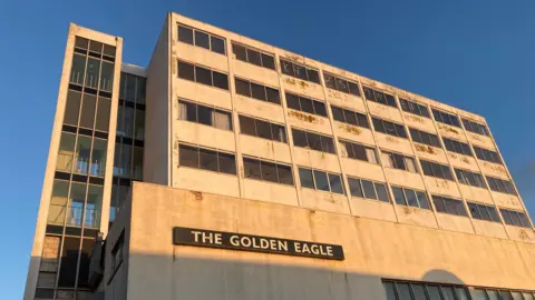 The exterior of the former Golden Eagle hotel. Plaster and paint on the front is crumbling while graffiti has been scrawled across some of the windows on the higher floors.