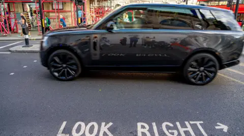 Getty Images A dark grey SUV drives past some traffic lights in London