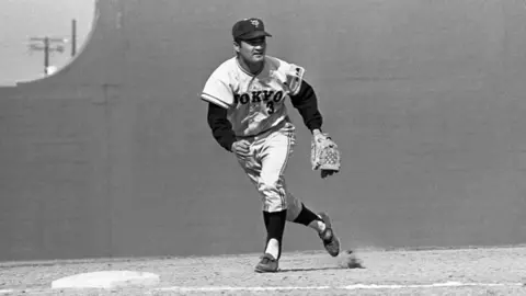 Getty Images A black and white photograph of Nagashima training on the baseball field. He is wearing the Giants uniform and a baseball cap.