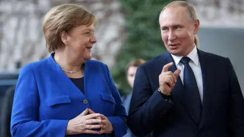 Getty Images Angela Merkel and Vladimir Putin smile as they address the UN summit in 2020.