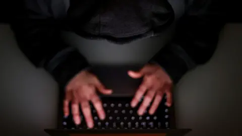 A laptop user with their hood up.