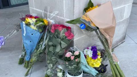 Peter Stewart/BBC Flowers left at the entrance to a flat.