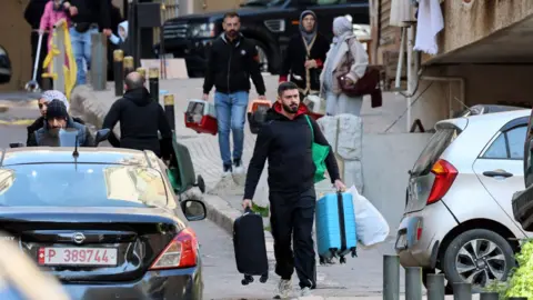 EPA People carry their belongings after fleeing their homes following Israeli air strikes in Beirut, Lebanon (9 March 2026)