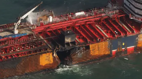 EPA-EFE/REX/Shutterstock Close up of the side of the Stena Immaculate showing a large hole in its hull and signs of fire damage to the deck