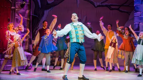 Sheffield Theatres Williams performing on stage in 2012 wearing blue britches and a stripey waistcoat