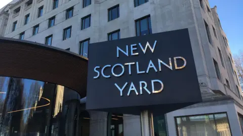 File image of the grey and silver three-sided New Scotland Yard rotating sign outside the Metropolitan Police's headquarters in London