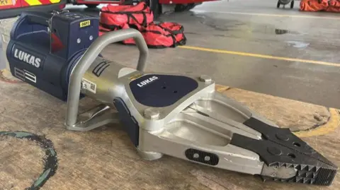 Nicola Hasler/BBC A close up of a spreader the fire service uses to open doors on vehicles that have been involved in road traffic collisions. It is positioned on the floor.
