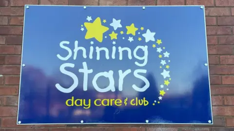 A bright blue sign with the words "Shining Stars" written across in big white letters.