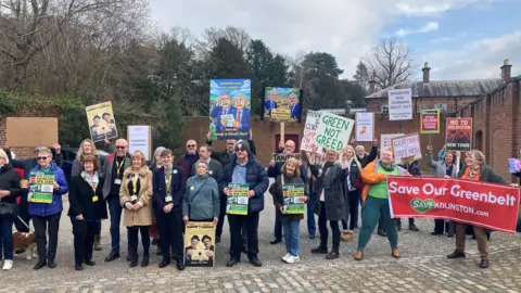 Protestors and Conservative councillors gathered outside Cheshire East Council's full council meeting at Tatton Park. They are holding banners against the Adlington new town plans and calling for the leader and deputy to resign
