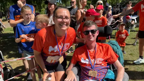 Craig and Ileshia Eskrett wearing training tops surrounded by support for the Run For MND