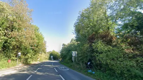 A generic image of a road in the middle of the photo. There are trees on both sides of the road in the image.