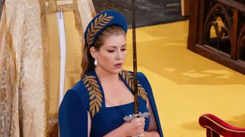 PA Media Penny Mordaunt holding a sword at the coronation of King Charles III