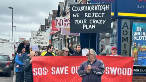 LDRS A group of people walking down the street holding placards and signs opposing the Portswood bus gate scheme.