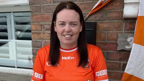 Niambh wearing an orange home Armagh jersey beside orange and white bunting outside her home