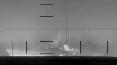 A black and white image of an Iranian warship through a scope