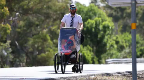 Ben Hodgart/Big Energy Productions A wide shot of Rob runnning, dressed in a cap, white shirt and striped tie, while pushing a pram.