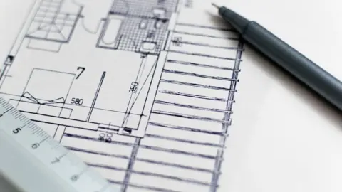 Pixabay A close-up of a blue print for a property. There is a pen resting on one corner of the drawing and a ruler resting on the other.