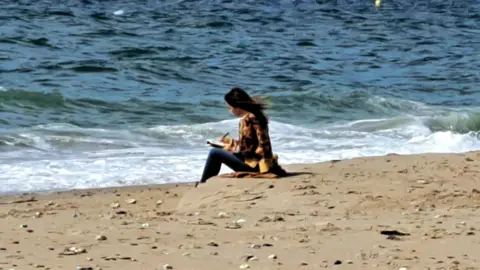 Lucy Clarke Lucy Clarke sitting on beach