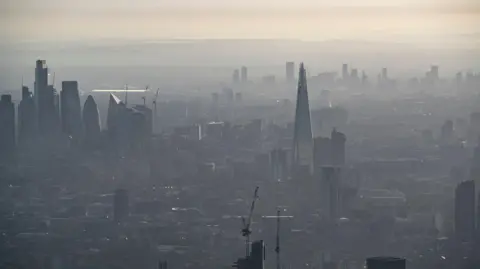 Getty Images A hazy aerial view of central London, with the Shard and other skyscrapers partially obscured by a haze under a pale sky.