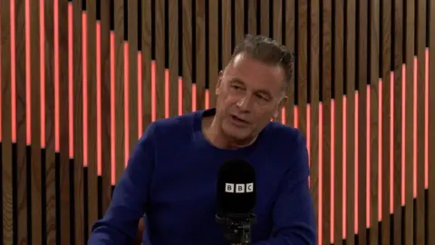 Chris Packham wearing a blue jumper in a BBC studio.